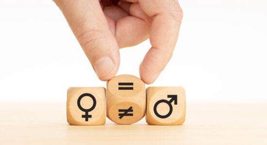 Gender equality concept. Hand turns a wooden block and changes a unequal sign to a equal sign between symbols of men and women